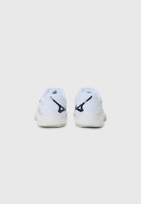 White athletic shoes with mesh upper, accented by black logo and grey detailing. Features padded collar and flexible rubber outsole.