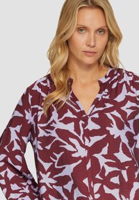 Bordeaux blouse met lavendel abstract patroon, lichtgewicht stof, relaxte pasvorm, ronde hals met knoopsluiting en lange mouwen.