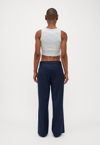 Top cropped cinza e calças largas azul-marinho, apresentando uma textura suave e um corte ajustado, com bolsos nas costas das calças.