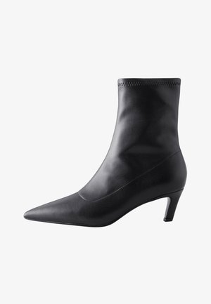 Stivaletto in pelle nera con punta appuntita e tacco sottile di altezza media, finitura liscia e bordo superiore cucito.