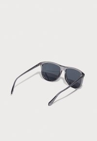 Ochelari de soare gri cu un cadru transparent, lentile întunecate și tempă elegante. Prezintă un hardware minim și un design unghiular pentru un aspect modern.