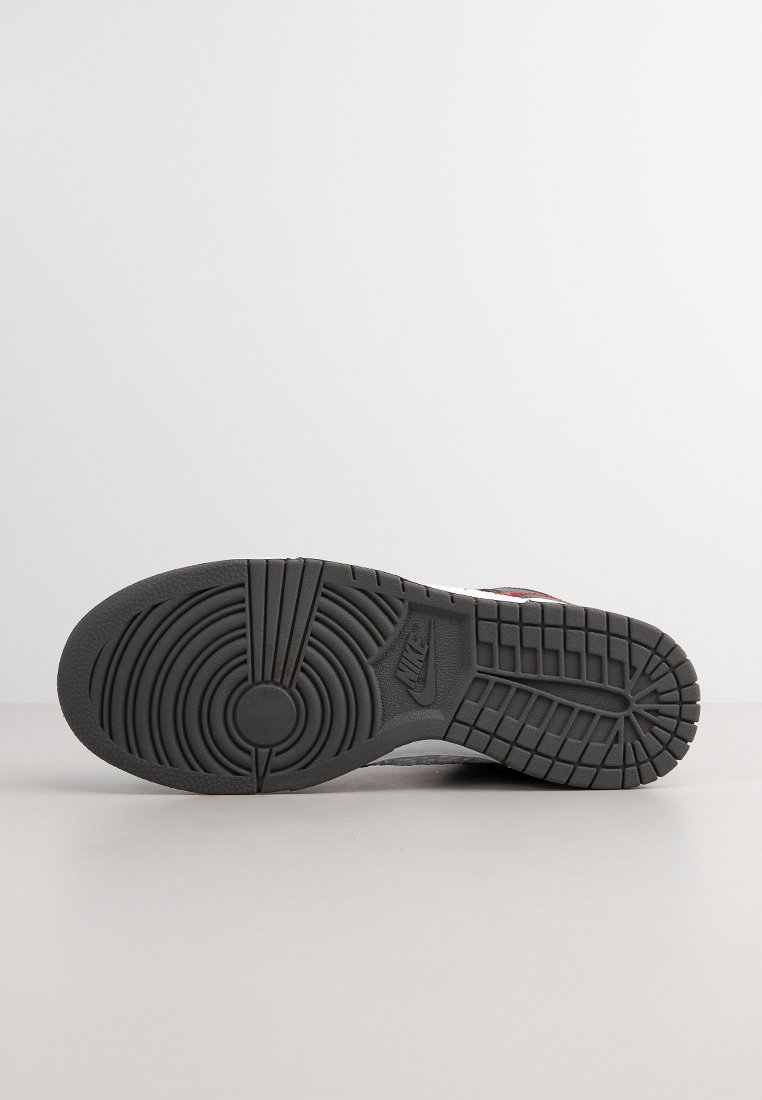 Semelle de sneaker Nike, en matériau caoutchouteux, de couleur grise, avec un motif texturé comportant des rainures circulaires et linéaires, arborant une empreinte de logo.