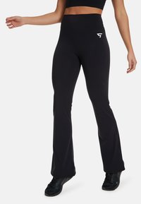 Black flared leggings made of stretchy fabric, featuring a high waistband and a small white logo on the hip.