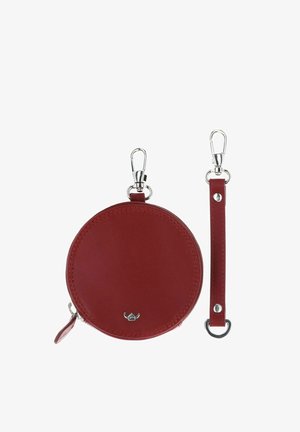 Pochette ronde en cuir rouge pour pièces avec fermeture éclair et bandoulière détachable, toutes deux dotées de fermoirs métalliques argentés pour une fixation sécurisée.