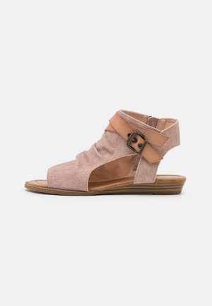 Chaussures avec une tige en tissu rose, design à bout ouvert et une sangle en cuir avec un accent de boucle. Semelle plate en bois avec un léger talon.