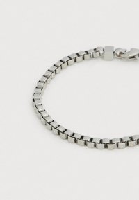 Brățară din metal argintiu cu zale pătrate, prevăzută cu închizătoare tip carabină. Finish neted și lustruit cu un design geometric uniform.