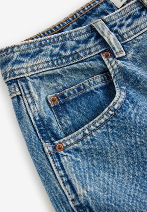 Blaue Jeans aus Denim mit subtilen Verfärbungen, kupferfarbener Hardware und orangen Nähten. Verfügt über eine Vordertasche und eine strukturierte Stoffoberfläche.