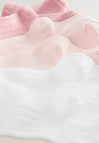 Stos miękkich bawełnianych skarpetek w białym i odcieniach różu, starannie ułożonych i lekko nachodzących na siebie na jasnej powierzchni.