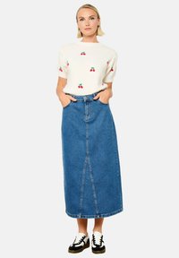 Balti megztinis su vyšnių raštais, derinamas su ilga mėlyna džinsine sijonų, turinčia priekines įpjovas. Dėvimi juodi ir balti sportiniai bateliai.