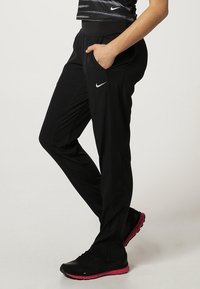 Black athletic pants with side pockets, elastic waistband, and a sleek design. Fabric appears lightweight and breathable, suitable for exercise.