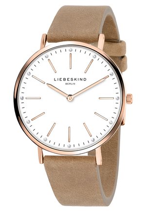 Montre analogique ronde avec un cadran blanc, des aiguilles en or rose et des index en cristal. Bracelet en suède beige. Design minimaliste avec une lunette en métal poli.