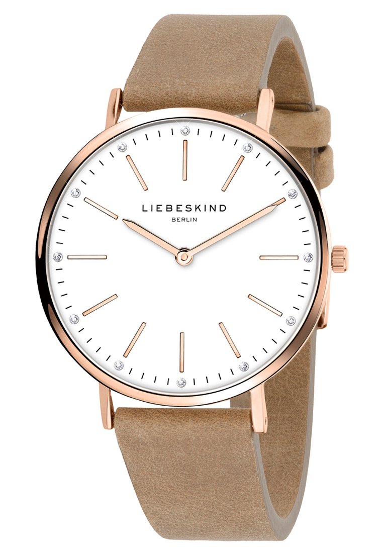 Montre analogique ronde avec un cadran blanc, des aiguilles en or rose et des index en cristal. Bracelet en suède beige. Design minimaliste avec une lunette en métal poli.