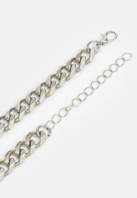 Silver metal chain bracelet featuring interlocking oval links and a lobster clasp, with an adjustable chain extension for sizing.