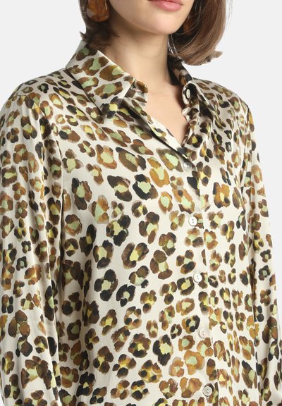 Blusa in satin con stampa leopardata; presenta un colletto classico, chiusura con bottoni e una vestibilità oversize con tonalità terrose di marrone, verde e crema.