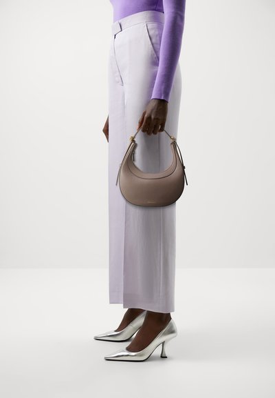 Sac à main de style hobo en cuir grainé taupe clair avec des accessoires en métal doré ; porté à la main. Assorti à un pantalon lavande et des escarpins argentés pointus.