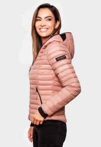 Vadderad rosa jacka med huva, med svarta accenter, blixtlåsade sidofickor och ribbade ärmslut. Strukturerad yta med horisontell sömnad.