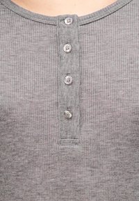 Γκρι πουκάμισο henley από ριμπ ύφασμα, με στρογγυλή λαιμόκοψη και πέντε κουμπιά με διαφανή κουμπιά κατά μήκος του μπροστινού μέρους.