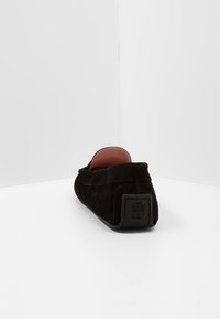 Czarne zamszowe buty typu slip-on z okrągłym noskiem i gładką powierzchnią. Posiadają wyściełane wnętrze oraz wytłoczone logo na pięcie.