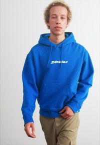 Sudadera azul de algodón con un bolsillo frontal y capucha con cordón. Logo de "Dickies" impreso en blanco en el pecho.