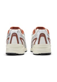 Λευκά αθλητικά παπούτσια με πορτοκαλί λεπτομέρειες, πλέγματα και υφασμάτινες υφές. Διαθέτουν μαλακές σόλες και στρογγυλεμένο τακούνι.