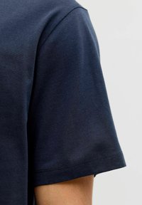 Camiseta de algodón azul marino con cuello redondo clásico y mangas cortas, textura suave y costuras cuidadas en el dobladillo y las mangas.