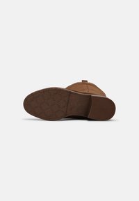 Brauner Schlupfstiefel mit einer strukturierten Gummisohle, ausgestattet mit einem glatten, weichen Obermaterial und einem verstärkten Nähmuster.