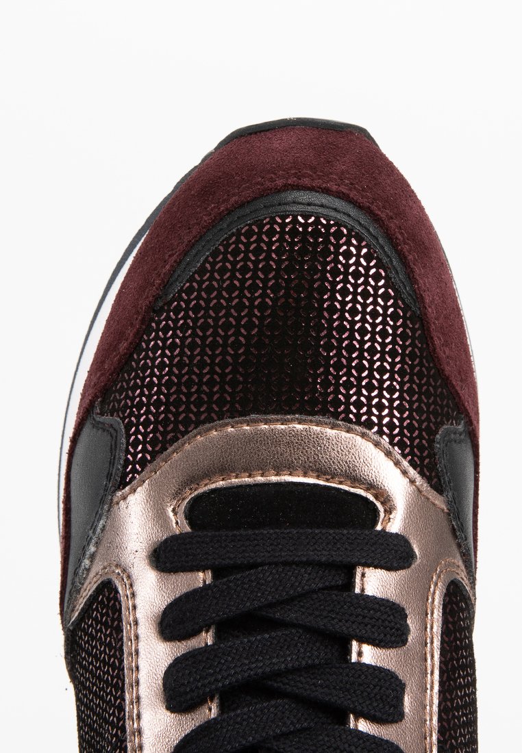 Sneaker mit einer bordeauxroten Wildleder-Toe-Kappe, seitlichen Paneelen in metallischem Roségold, schwarzen Mesh-Akzenten und schwarzen Schnürsenkeln. Strukturierte Oberfläche mit synthetischen Materialien.