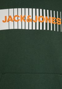 Felpa verde con testo "JACK & JONES" bianco e arancione sul petto, decorata con motivi a righe orizzontali. Tessuto morbido e strutturato.