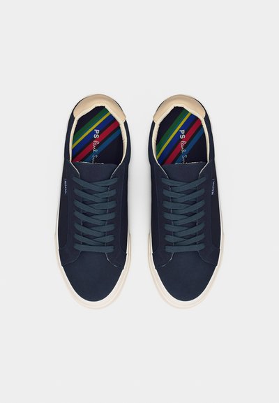 Ζευγάρι σκούρα μπλε αθλητικά παπούτσια με κορδόνια, λευκές σόλες και πολύχρωμες ριγέ εσωτερικές σόλες, φωτογραφημένα από πάνω σε λευκό φόντο.