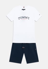 Λευκό βαμβακερό μπλουζάκι με εκτύπωση "TOMMY HILFIGER" σε μπλε ναυτικό και κόκκινο. Συνδυάζεται με σορτς σε μπλε ναυτικό, με κορδόνι που έχει κόκκινες, λευκές και μπλε λεπτομέρειες.