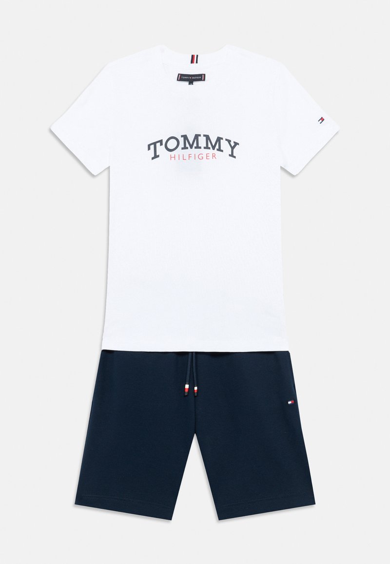 Λευκό βαμβακερό μπλουζάκι με εκτύπωση "TOMMY HILFIGER" σε μπλε ναυτικό και κόκκινο. Συνδυάζεται με σορτς σε μπλε ναυτικό, με κορδόνι που έχει κόκκινες, λευκές και μπλε λεπτομέρειες.