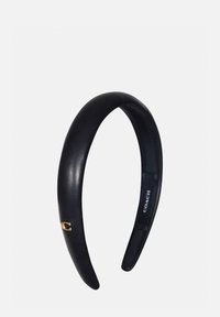 Bandeau en cuir noir avec une texture subtile, arborant un petit logo "C" doré sur le côté. Design simple et élégant, adapté à divers styles.
