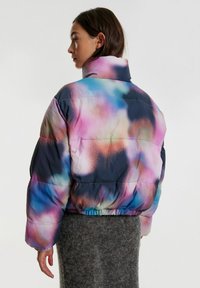 Multicolore pufferjack in een pastelverloop, met een hoge kraag en elastische zoom, gemaakt van glanzende, lichtgewicht stof.