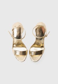 Goldene metallische Absatzsandalen mit Schlangenhautmuster, offener Spitze und Knöchelriemen. Sie verfügen über eine glänzende Oberfläche und eine glatte, reflektierende Struktur.