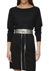 Zwarte gebreide jurk met lange mouwen, voorzien van een metallic zilveren riem die in de taille is gestrikt. Textuurstof en eenvoudige ronde halslijn.