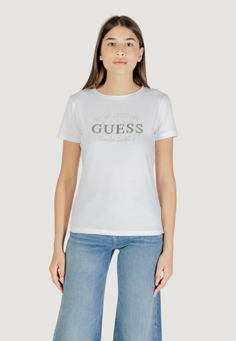T-shirt in cotone bianco a maniche corte, con logo argentato "GUESS" e stampa "Established 1981". Tessuto liscio, vestibilità standard.