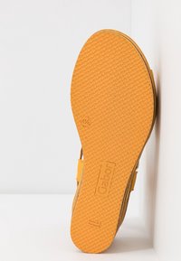Semelle d'une sandale jaune montrant une semelle texturée, taille 41,5, marque Gabor, et "Made in Portugal" estampillé en dessous.