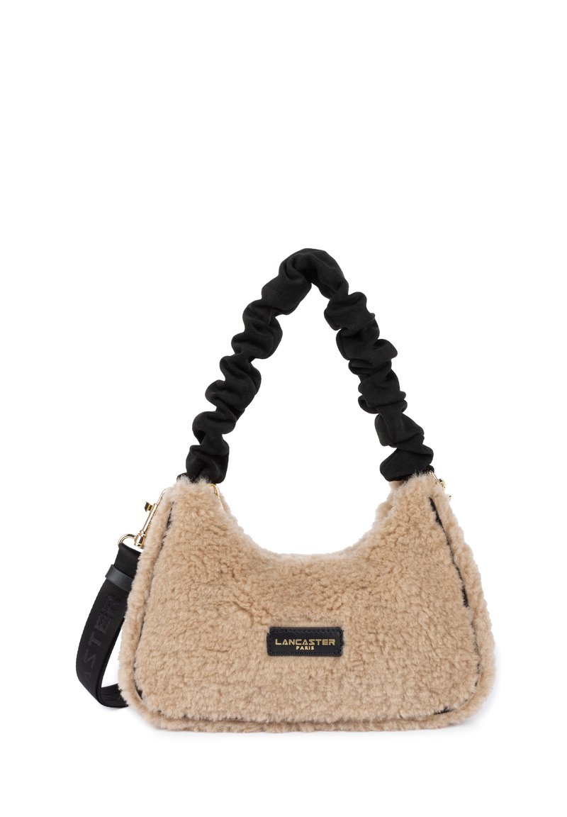 Beige nepbont handtas met een zachte textuur, zwarte gerimpelde handgreep en gouden hardware. Heeft een rechthoekige vorm en een merketiket.