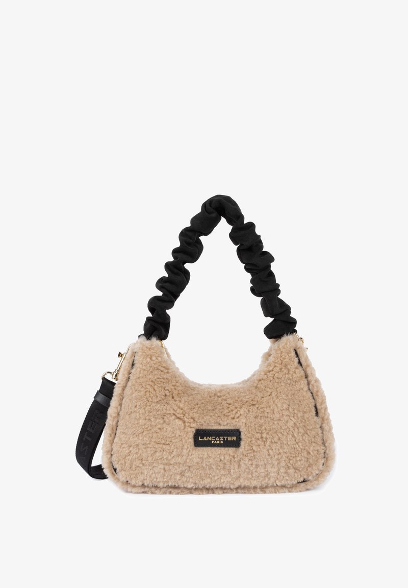 Borsa a tracolla in pelliccia sintetica beige con una texture morbida, manico arricciato nero e accessori dorati. Presenta una forma rettangolare e un'etichetta del marchio.