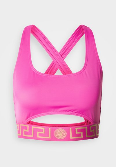 Ružová športová podprsenka s dizajnom na kríž na chrbte a výrezom pod prsiami. Na elastickom páse je zlatý metalický vzor gréckeho kľúča.