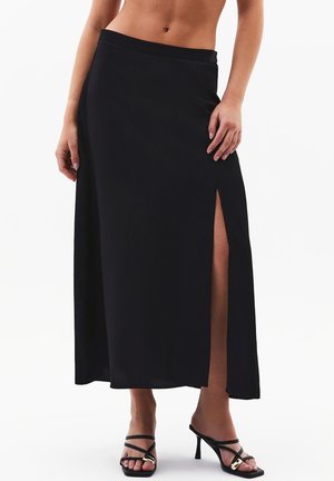 Jupe longue noire avec une fente latérale, en tissu lisse. Comprend une ceinture ajustée et s'élargit jusqu'au sol en forme trapèze.
