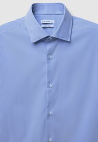 Camicia slim-fit blu chiaro con sottili righe verticali bianche e un colletto classico, parzialmente abbottonata sul davanti.