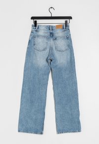 Lichtblauwe wijde jeans met een vervaagde afwerking, voorzien van twee achterzakken en een leren patch op de tailleband.