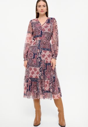 Langes gedrucktes Kleid mit V-Ausschnitt, langen transparenten Ärmeln und elastischem Bund. Es zeigt Paisley- und Blumenmuster in Rot und Marineblau.