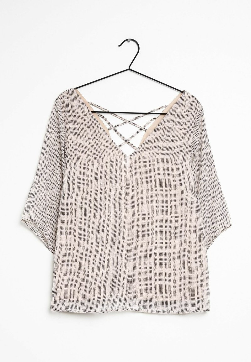 Blusa leggera e strutturata con scollatura a V e dettagli incrociati sul retro. Presenta una palette di colori neutri con un motivo delicato.