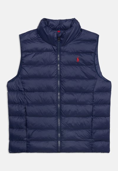 Μπλε σκούρο καπιτονέ αμάνικο μπουφάν με φερμουάρ μπροστά και κόκκινο κεντητό λογότυπο στο αριστερό στήθος.