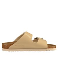 Ciabatta in gomma beige con due larghe fasce, un plantare in sughero e una suola testurizzata. Presenta una fibbia in metallo sulla fascetta esterna.