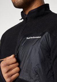 Czarna polarowa kurtka z półrozpięciem, z kontrastową czarną nylonową kieszenią na piersi z logo "PeakPerformance".