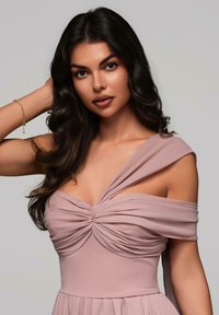 Rosa klänning i blush med draperad off-shoulder design, samlad boströja och flytande kjol. Slät tygstruktur med plisserade detaljer.