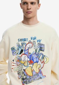 Crème sweatshirt met een graphic van Donald Duck, tekst "Sorry voor mijn slechte humeur," met kleurrijke accenten en een gestructureerde print.